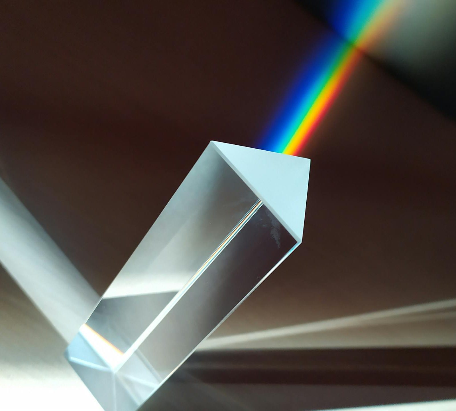 A glass prism creates a vivid rainbow reflection, capturing abstract geometric beauty.